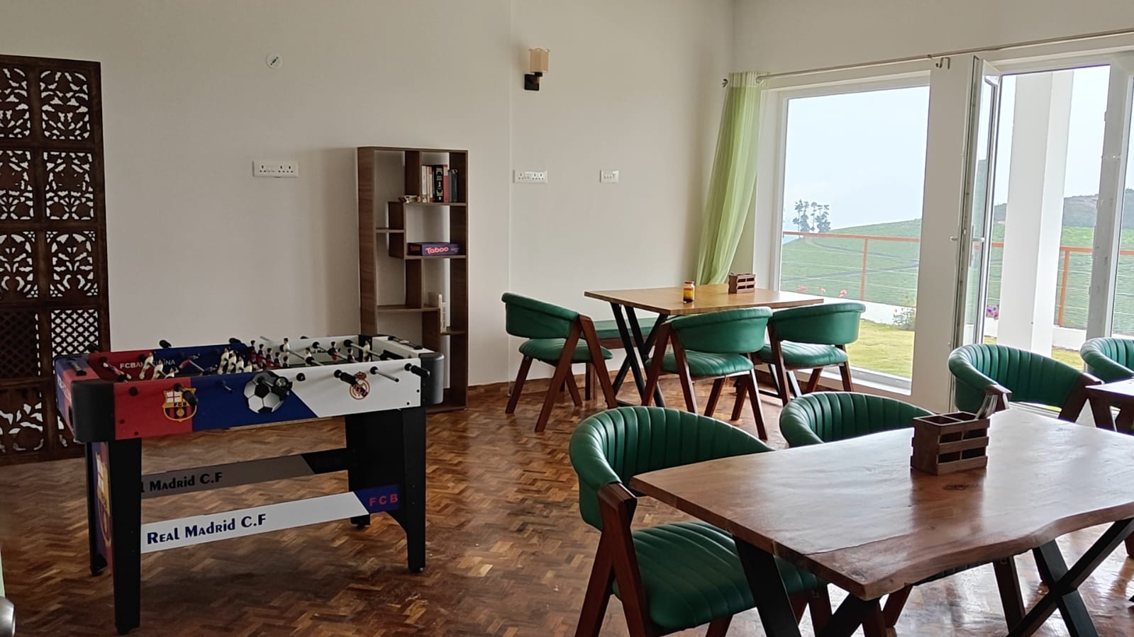 The games area with its foosball table and shelf of board games, doors open to the lawn